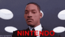 a man in a suit and tie is standing in front of a nintendo sign