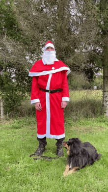 a man dressed as santa claus is standing next to a dog