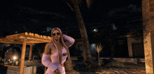 a woman in a pink dress is standing in front of a palm tree at night