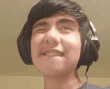 a young man wearing headphones is smiling and making a funny face