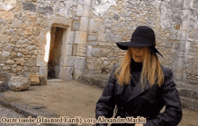 a woman wearing a black hat is standing in front of a stone wall with the words outre tombe haunted earth