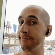 a bald man wearing a pair of ear buds with the letter n on them