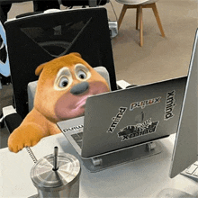 a cartoon bear is sitting at a desk in front of a laptop .