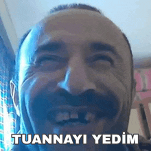 a man with a beard is laughing with the words tuannayi yedim written on the bottom of his face .