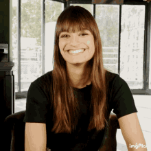 a woman in a black shirt is smiling in front of a window with imgplay written on the bottom