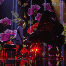 a man in a suit is playing a piano on a stage with flowers in the background and the word talent on the bottom