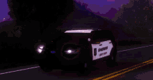 a sheriff 's car is driving down a road with purple lights