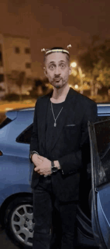 a man in a black suit is standing in front of a car