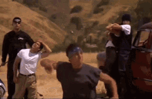 a group of men are standing in a field and one of them is wearing a bandana with the word los angeles on it