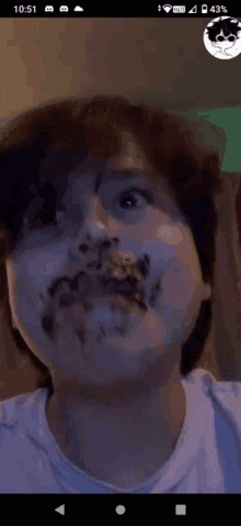 a person with chocolate on their face is making a funny face on a cell phone .