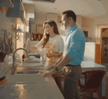 a man and woman are washing dishes in a kitchen sink