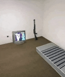 a bedroom with a mattress a television and a rifle