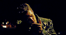 a man in a leather jacket is smoking a cigarette at night .