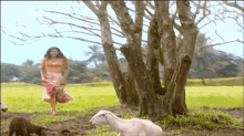 a woman in a pink dress is running in a field with a goat