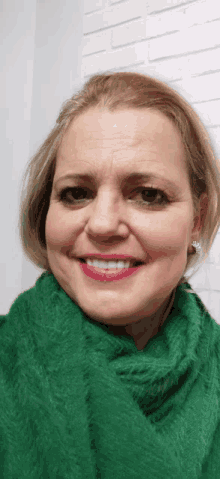 a smiling woman wearing a green scarf and earrings