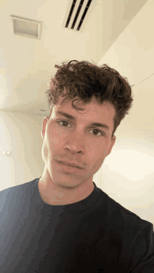 a man with curly hair is wearing a black t-shirt