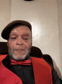 a man with a beard wearing a red vest and bow tie