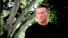 a blurry picture of a man in a black shirt standing under a tree