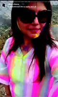 a woman wearing sunglasses and a rainbow colored shirt is taking a picture