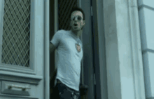 a man wearing sunglasses and a white t-shirt is standing in a doorway