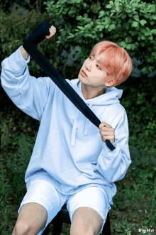 a boy with pink hair is wearing a blue hoodie