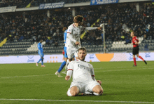 a soccer player kneeling on the field wearing a fly emirates shirt