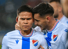 two soccer players are hugging each other and one of their shirts says bank of finland on the front