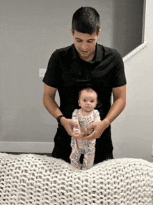 a man in a black shirt holds a baby