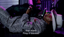 a man in a leopard print shirt and cowboy hat is laying on the floor and says man down pimp in distress .