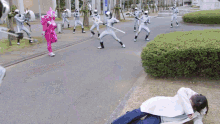 a girl in a pink costume is laying on the ground in front of a group of ninjas holding swords