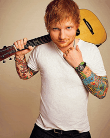 ed sheeran is holding a guitar over his shoulder