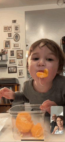 a young boy is eating an orange peel during a video call with his parents