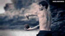 a man without a shirt is holding a football in his hand .