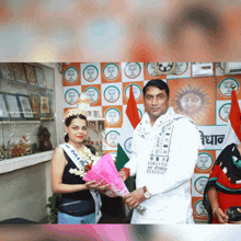 a woman wearing a miss india sash is being presented with flowers by a man