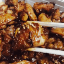 a close up of a chicken dish with chopsticks