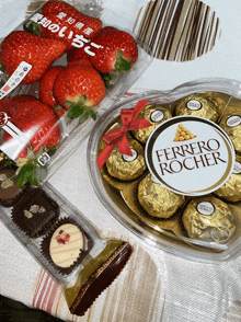 a container of ferrero rocher sits on a table next to a container of strawberries