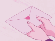 a person is holding a pink envelope with a pink heart on it .