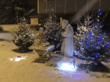 a nativity scene is surrounded by snow covered trees