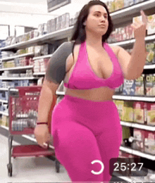 a woman in a pink top and pink pants is walking in a store .