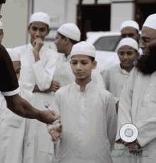 a group of young men wearing white shirts and hats are standing in front of a sign that says ' islamic ' on it