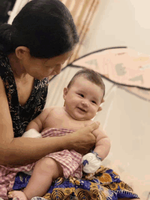 a woman holds a baby in her arms and the baby is smiling