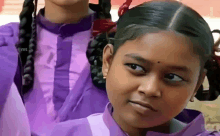 a girl wearing a purple shirt looks at the camera