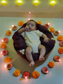 a baby in a basket surrounded by lit candles and flowers