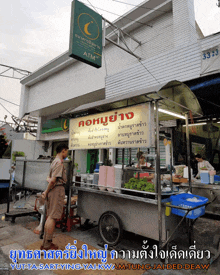 a man stands in front of a food cart with a sign that says " atm "