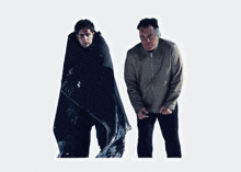 two men are standing next to each other and one has a blanket on his back