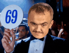 a man in a tuxedo is holding up a sign that says 69