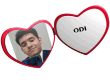 a man taking a selfie in a heart shaped mirror with the name odi on it