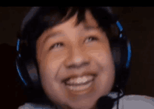 a young boy wearing headphones is smiling and looking up .