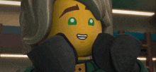 a close up of a lego character with green eyes and a smile on his face .