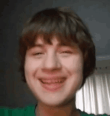 a young boy wearing a green shirt is smiling for the camera .